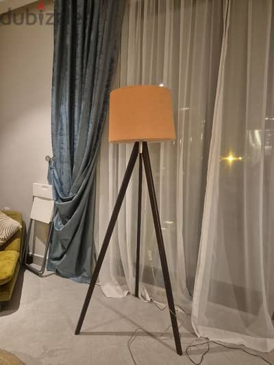 tall lamp with wooden legs and orange lamp shade